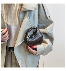 Macro detail of vertical stripe texture and circular handle on brown acrylic clutch