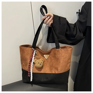 Detail of contrast stitch tote bag with suede texture and decorative bear keychain charm