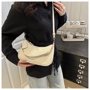 Detail of cream woven crescent bag with gold chain handle and adjustable leather strap