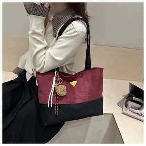 Detail of burgundy vintage tote bag with bear charm on a model in a minimal setting