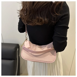 Detailed shot of a pink woven texture shoulder bag with golden chain and leather handle