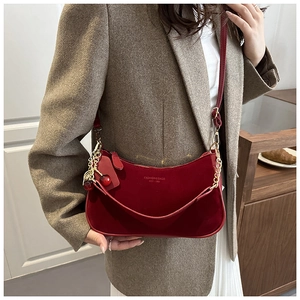 Detail of red suede half-moon bag featuring gold chain and signature cherry charm