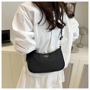 Detail of black crescent shoulder bag with diagonal stripe texture and gold lettering