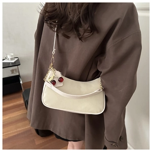 Détail du sac hobo blanc cassé avec breloque cerise et chaîne dorée sur mannequin