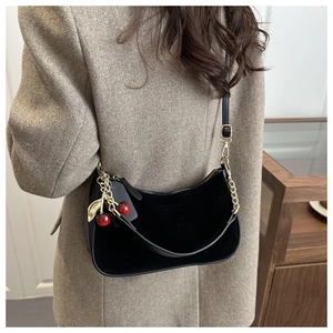 Détail du sac bandoulière en cuir noir avec breloque cerise et chaîne dorée