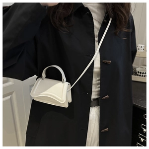 Dettaglio di una mini borsa quadrata in pelle bianca indossata da una modella