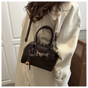 Detail of vintage brown leather bowling bag with gold hardware and bell charm