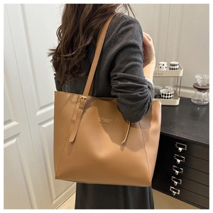 Close-up of a large khaki leather tote bag with a fashion leather label and adjustable strap