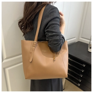 Detail of vintage brown leather tote bag showing textured strap and embossed fashion logo