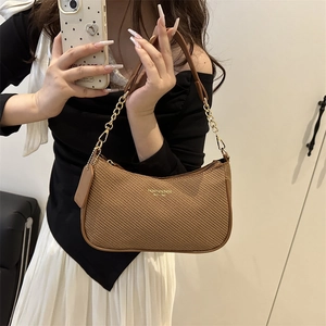 Brown woven hobo bag with gold chain strap and leather handle in a lifestyle setting