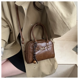 Brown vintage leather crossbody bag with golden horsebit detail and woven charm