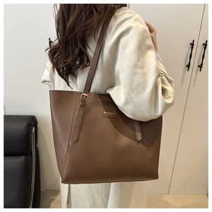 Detail of adjustable shoulder strap and gold metal plate on a brown tote bag