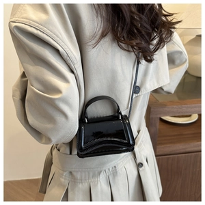 Close-up of black patent leather mini handbag with a unique wavy flap and top handle