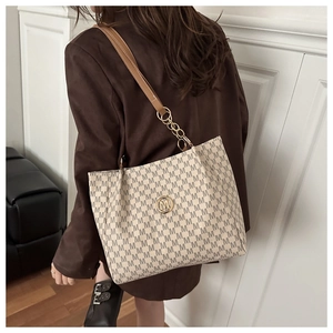 Detail view of large tote bag with brown monogram print and gold metal logo on beige leather