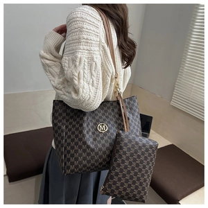 Détail du grand sac cabas marron avec motif M et logo doré porté par un mannequin femme