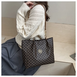 Détail du sac cabas marron à motif M avec logo métallique doré et bandoulière chaîne