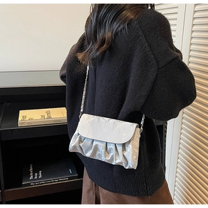 Detail of silver metallic pleated bag with chain strap styled with black sweater