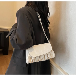 Close-up of pleated cloud bag in off-white with chain strap worn on shoulder