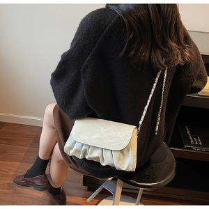 Detail of marble pattern shoulder bag with pleated base and leather chain strap worn by model