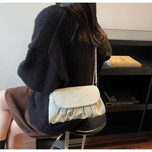 Detail of cream pleated cloud bag featuring metal chain strap and soft leather texture