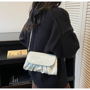 Detail of light green pleated cloud bag featuring glossy marble texture and silver chain