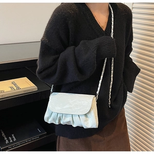 Detail of light textured pleated cloud bag with silver chain strap on model shoulder