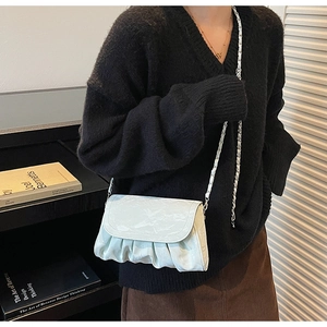 Detail of a ruffled cloud shoulder bag with glossy crocodile texture and chain strap