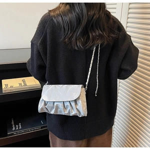 Close-up of silver pleated crossbody bag with metallic texture and elegant chain strap