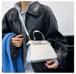 Silberne Handtasche mit Kroko-Prägung und goldenem Drehverschluss zur schwarzen Lederjacke