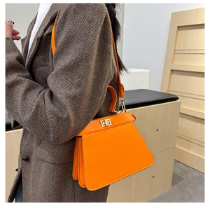 Dettaglio borsa Kelly arancione coccodrillo con chiusura dorata e texture in pelle PU