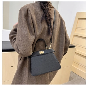Primer plano de bolso Kelly negro con relieve de cocodrilo, cierre dorado y textura de piel