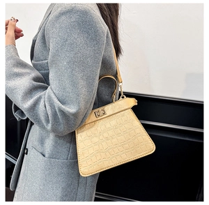Detalle de bolso beige con relieve de cocodrilo y cierre de giro metálico dorado de lujo
