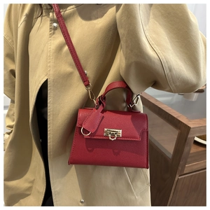 Detail der roten Mini-Handtasche mit Litschi-Struktur und goldenem Schloss am Mantel