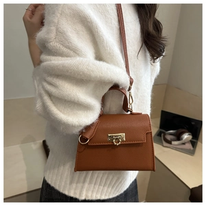 Brown litchi grain leather crossbody bag shown on model in cozy office setting