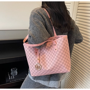 Detail of a pink monogram tote bag with gold M-logo charm and stylish printed leather texture