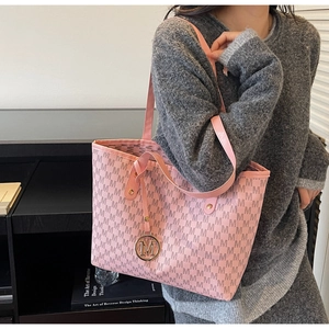 Detailed close-up of pink tote bag featuring M-pattern print and gold letter charm