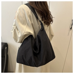 Detailed back view of a minimalist black oversized tote bag worn by a model in a studio