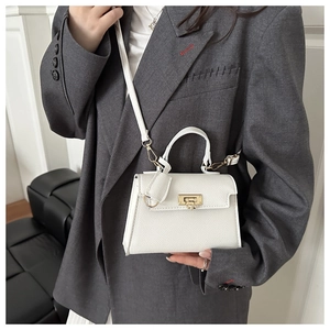 Detailed close-up of white pebble leather mini bag with gold lock and thin shoulder strap