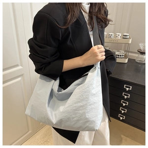 Détail du sac hobo en nylon bleu clair à texture plissée avec bandoulière noire large