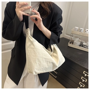 Détail du grand sac bandoulière léger en nylon crème porté par un mannequin femme