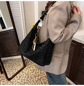 Close-up of leopard print crossbody bag with ethnic wood bead and tassel charms