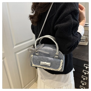 Détail du sac oreiller en denim gris avec dentelle blanche et nœud argenté élégant