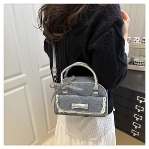Detail of grey denim pillow bag with lace trim, silver bow, and checkered ribbon accents