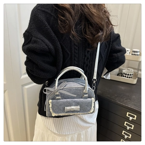 Détail du sac bandoulière gris argenté avec dentelle, nœuds et sangle sur pull noir