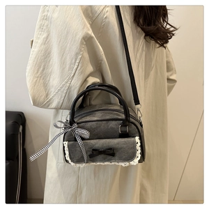 Grey denim bowling bag with lace trim and bow accent shown on model side view
