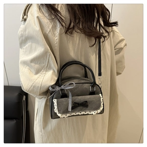 Detail of grey denim boston bag featuring white lace trim and black bow decorative accents