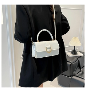 Detail of white leather shoulder bag with gold U-shaped buckle on black blazer