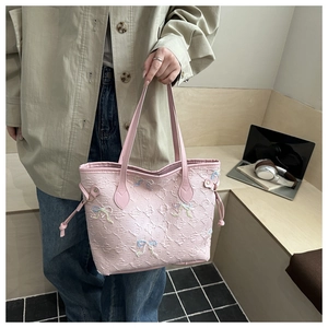 Detailed texture of pink woven tote bag with embroidered bows and side drawstring ties