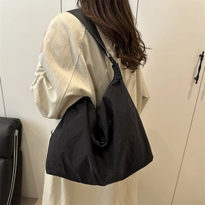 Grand sac à bandoulière en nylon noir avec texture plissée porté par un mannequin chic