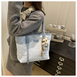 Détail du sac cabas bleu clair avec texture florale et breloque peluche ours mignonne